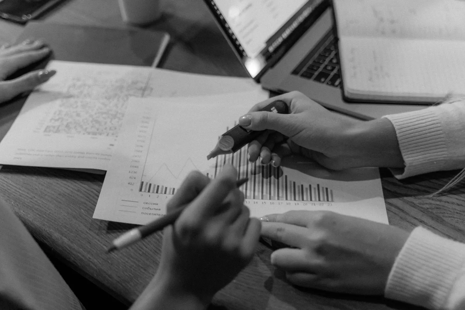 Manos trabajando sobre gráficas y un cuaderno